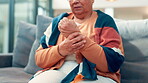 Wrist pain, cramps and hands of old woman on sofa for osteoporosis, joint injury and inflammation. Arthritis symptoms, fibromyalgia and sprain with person in living room of home for risk and strain