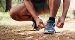 Man, hands and tie with shoes in forest for hiking, fitness preparation or outdoor run in nature. Closeup, male person or runner getting ready with sneaker or tying laces for trekking or exercise