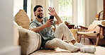 Video call, wave and man in house with phone, hello and online conversation in living room. Digital, happiness and male person on lounge floor with technology, kiss and connection on chat app.
