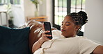 Black woman, phone and relax on sofa, texting and scroll with contact, web chat or notification in home. African person, smartphone and click on mobile app, smile and post on social media at house