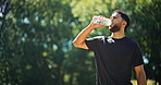 Thirsty, man and drink water in nature with walk for sports hydration, exercise break or thinking. Bokeh, person outdoor and reflection with beverage for electrolytes, training recovery and wellness.