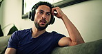 Relax, headphones and man on sofa in home listening to music for depression, sad or mental health. Upset, audio tech and male person with playlist or radio for emotions in living room at apartment.