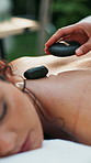 Hands, woman and hot stone massage for back at spa, relax and holistic treatment at holiday resort. People, lava rock and service for client with rest, rehabilitation or physical therapy at lodge