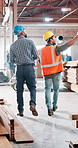 Men, carpenter and inspection at factory, discussion and point for safety, architecture and builder at workshop. People, business owner and contractor with back, job or review for warehouse expansion