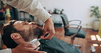 Man, shaving cream and beard at salon with blade, facial hair removal and product at small business. People, barber and client with customer experience, foam and razor with trim at barbershop