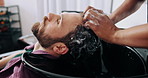 Man, relax and washing hair in salon with foam for maintenance, hygiene and grooming appointment. People, hairstylist and clean client scalp in small business with shampoo, massage and treatment.