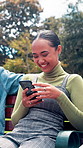 Friends, people and laughing with phone at park for funny group chat, social media meme and texting. Relax, gen z girls and scroll with smartphone on bench for internet joke and comic status update