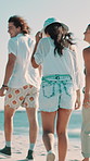 Back, beach and friends walk for vacation, holiday and adventure by ocean paradise. Seashore, people and travel on summer trip for tourism, bonding together and outdoor on tropical island with wind