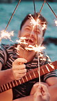 Friends, beach and hands with sparklers for guitar, smile and reunion for celebration in nature. Summer holiday, social gathering or hangout with people, party and fireworks for music together