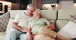 Senior couple, relax and laugh in lounge, people or talking with smile in house, retirement and love. Happy, elderly man and embrace with old woman in living room, affection and romance with partner