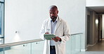 Healthcare, tablet and walking with doctor black man in hospital for planning or research. App, medical and reading with mature African person in clinic hallway for insurance or review of information