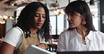 Women, waitress and conversation in cafe with tech for digital menu development, planning and feedback. People, manager and employee in coffee shop with tablet, laptop and discussion for hospitality.