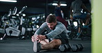 Workout, legs and man stretching in gym for fitness, training or wellness routine in morning. Health, athlete and male person with warm up exercise for preparing muscles on floor in sports center.