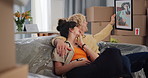 Couple, photo frame and relocation at new home on sofa, embrace and decision for artwork in lounge. Man, woman and happy on couch, discussion or painting with moving, boxes and real estate investment