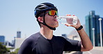 Cycling, rest and man in city drinking water, hydration and break in training routine. Fitness, exercise and cyclist in urban area with bottle, h2o liquid and health detox in workout recovery.