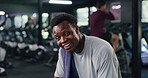 Breathing, face and fitness with tired man in gym for break, recovery rest or wellness. Exercise, fatigue or intensity with exhausted and happy athlete in health club for training or workout routine