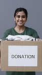 Face, woman or clothes in donation box for non profit, community care or volunteer in studio. Cardboard, charity or happy person giving package for help, aid or portrait to support on gray background