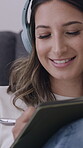 Writing, headphones and online class with woman on sofa for distance learning, education and research. College webinar, streaming and notes with person in living room of home for report and review