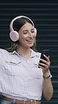 Happy woman, dancing and listening with headphones or phone for music on garage door. Female person, user or smile with songs, sound or mobile smartphone for audio streaming app, energy or vibe