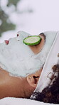 Woman, relax and face mask in beauty spa with cucumber for antioxidants, collagen or anti aging benefits. Person, rest or facial cream at resort with treatment for hydration, dermatology or wellness.
