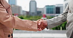 Business people, meeting and handshake with introduction in city for greeting or meeting. Closeup, employees or colleagues shaking hands with agreement, deal or b2b for partnership in an urban town