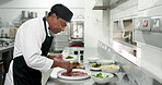 Food, presentation and man with garnish, kitchen or culinary skills for meal prep, chef and process. Plating, cook and person with ingredients for cuisine, fine dining and hospitality in restaurant