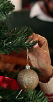 Couple, hands and christmas tree with bauble for festive decoration or celebration together in home. Closeup, man and woman with sparkle ball or decor for december holiday or santa tradition in house