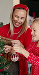 Christmas, mother and girl with tree for decoration with festive holiday, tradition or help. Daughter, excited woman and ornament in family home for celebration, happiness and bauble for bonding