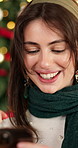 Smile, woman and relax with phone at house on Christmas for social media, gift search and texting. Happy, female person and mobile for online shopping, funny meme and festive celebration with bokeh

