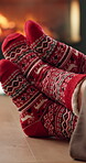 Fireplace, feet and couple with festive socks for holiday celebration, matching clothing and romance. Christmas season, cozy winter and people with affection by flames, support and connection in home