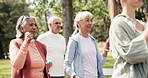 Senior group, walking and dumbbells with personal trainer in park for cardio exercise or workout. Elderly people, coach or training with weight for physical activity, health or wellness in nature