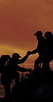People, silhouette and helping hand for hiking on mountain at sunset, friends and support on adventure. Men, teamwork and lift on rocks, hill or outdoor in summer with trekking challenge in nature