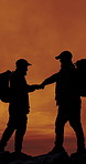 People, silhouette and fist bump for hiking, sunset sky and friends on mountain, space or adventure. Men, teamwork and success on rocks, hill or celebration in summer for trekking challenge in nature