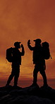 People, silhouette and high five for hiking at sunset on mountain, friends and space on adventure. Men, teamwork and success on rocks, hill or celebration in summer for trekking challenge in nature