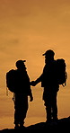 People, hiking and silhouette with handshake for backpacking night or outdoor adventure together. Active, male people or hikers shaking hands with bag on mountain for trekking journey in nature