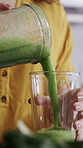 Woman, hands and blender with green juice or smoothie for nutrition, vitamins or diet in home. Closeup, female person or nutritionist pouring ingredients with organic food for health detox in house