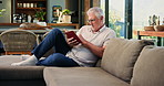 Reading, book and senior man on sofa to enjoy literature, story and literacy in home. Retirement, living room and elderly person relax with novel for me time, hobby and fiction for knowledge in house