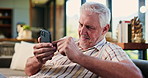 Cellphone, relax and senior man on sofa in home with texting, social media or chatting on mobile app. Happy, technology and elderly male person with phone for reading blog post in living room.