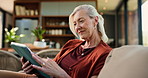 Tablet, relax and senior woman on sofa in home with reading comedy blog on app for entertainment. Laughing, digital technology and elderly female person on social media in living room at house.