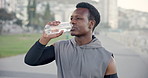 Black man, fitness and drinking with water in city for workout break, hydration or recovery. Active, male person or runner with mineral liquid, bottle or aqua beverage for sustainability on promenade
