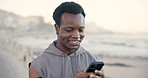 Exercise, ocean and black man with smartphone, smile and digital app to track progress. Person, fitness or athlete with cellphone, beach or internet for social media, connection or message to contact