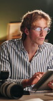 Computer, photography and tablet with man in office at night for artistic or creative career. App, camera and development with photographer person at desk in dark digital agency for project deadline