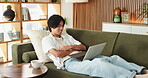 Relax, happy man and laugh with laptop on couch, funny movie and watch comedy series for entertainment. Online streaming, comic film or asian person in home to rest, subscription platform or computer
