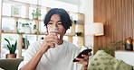 Man, phone and drinking water on couch with texting, relax and home with web chat in living room. Person, smartphone and glass for hydration on sofa, mobile app or scroll on social network at house