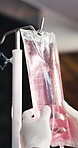 Doctor, hands and medicine in clinic with iv drip, treatment or detox preparation for hydration benefits. Healthcare worker, person and wellness with intravenous fluid, natural remedy or supplements.