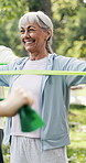 Fitness class, resistance band and elderly woman at park for health, workout and smile with bokeh. Senior person, equipment and stretching outdoor for exercise, wellness and retirement with coach