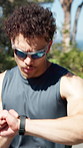 Runner, check time and man with fitness, sunglasses and cardio workout with challenge. Wellness, exercise or person in street, running and smart watch to track progress, health or training in Canada