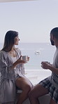 Couple, coffee and window in bedroom with ocean view for bonding, relax and vacation at hotel. Happy man, woman and relationship with beverage, drinks and connection on holiday at seaside resort