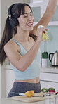 Woman, singing and headphones in kitchen with blender, streaming and citrus juicer for mic in home. Person, happy and audio with karaoke, playful and dancing with smoothie ingredients at apartment