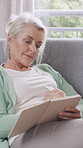 Journal, writing and senior woman in home with notebook for reflection, planning and ideas on sofa. House, retirement and person with diary for inspiration, thoughtful and wondering in living room